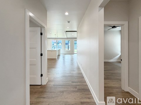 A spacious hallway with wooden floors and white walls.