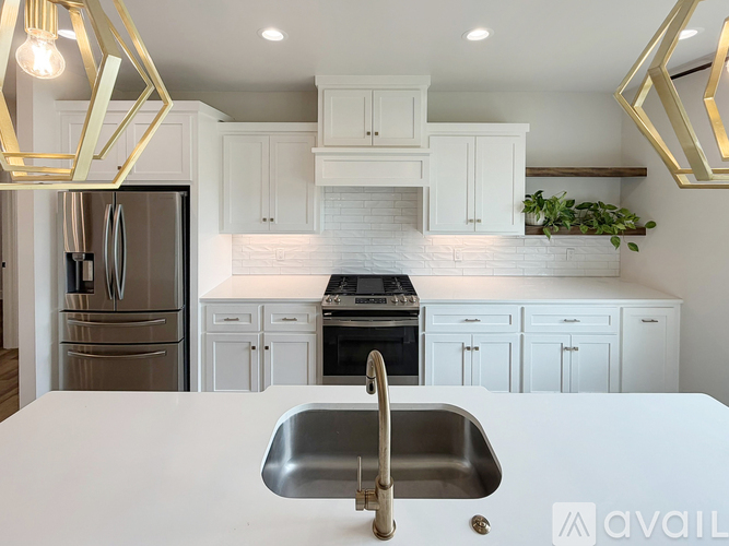 A modern kitchen with a stainless steel sink and white cabinets.