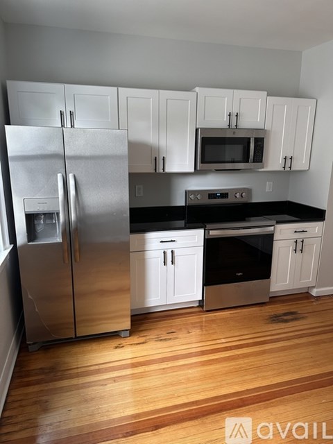 A kitchen with a refrigerator, microwave, oven, and cabinets.