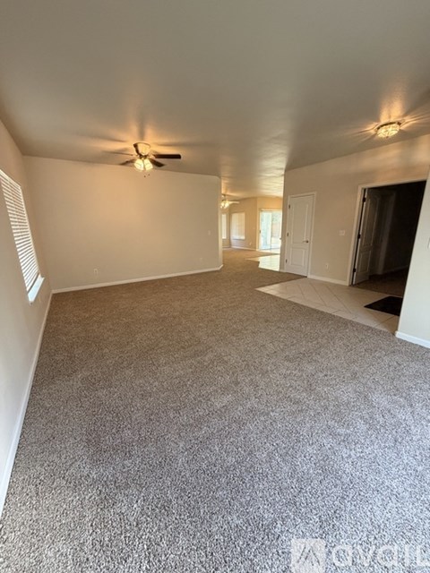 A spacious room with a ceiling fan and carpeted floor.
