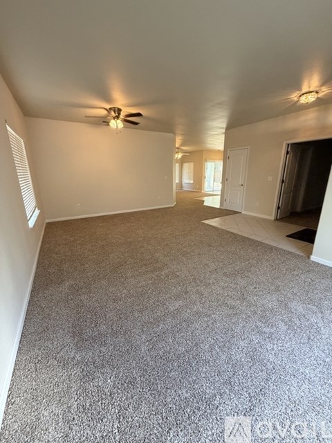 A spacious room with a carpeted floor and a ceiling fan.