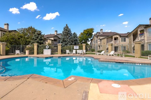 A swimming pool surrounded by a fence and chairs.