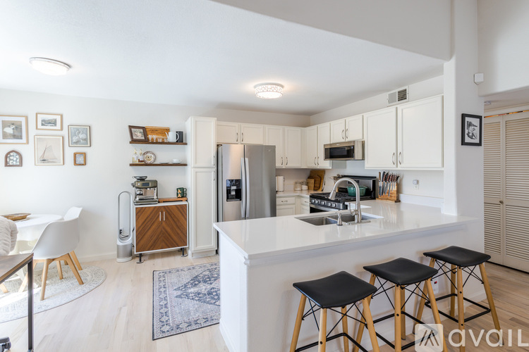 A kitchen with white cabinets and a white island with black stools.