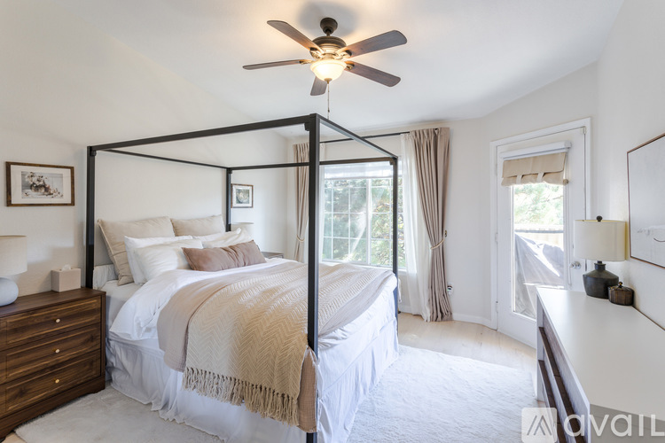 A bedroom with a four poster bed and a ceiling fan.
