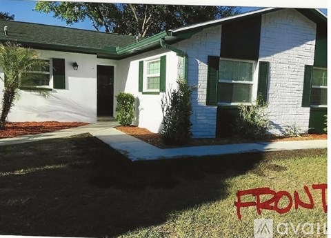 A white house with green shutters is for sale.