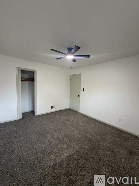 A room with a ceiling fan and carpeted floor.