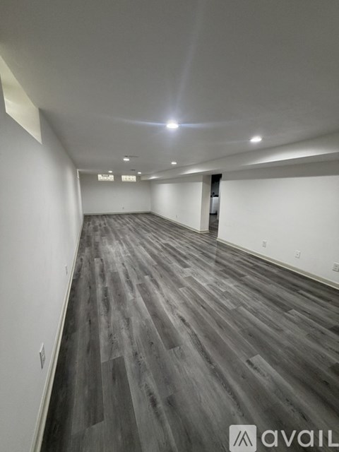 A long hallway with wood flooring and white walls.