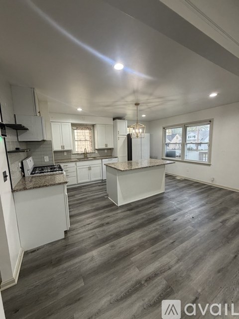 A kitchen with white cabinets and a wooden floor.