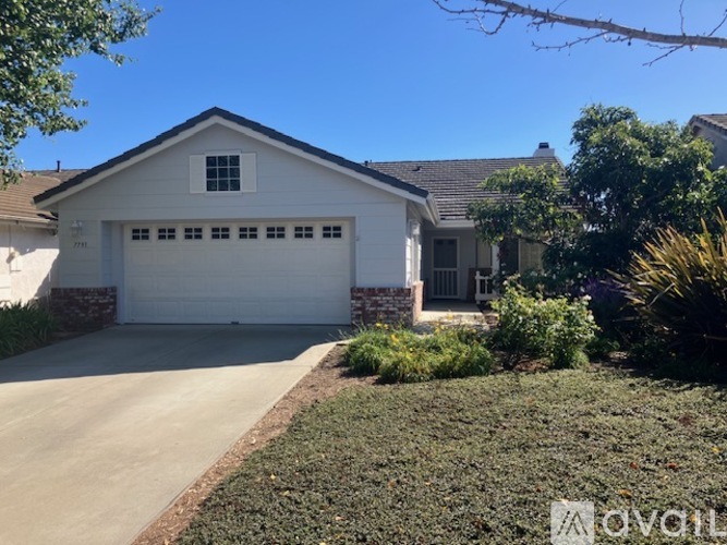 A white house with a garage door and a driveway.
