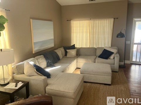 A living room with a large couch and a painting of a beach on the wall.