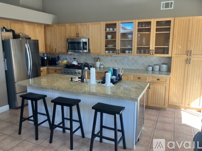 A kitchen with a granite countertop and black stools.