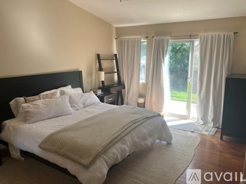 A bedroom with a large bed and a sliding glass door leading to a balcony.