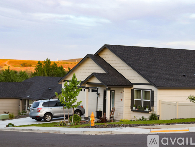A house with a car parked in front and a fire hydrant to the left.