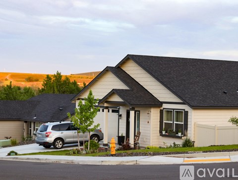 A house with a car parked in front and a fire hydrant to the left.