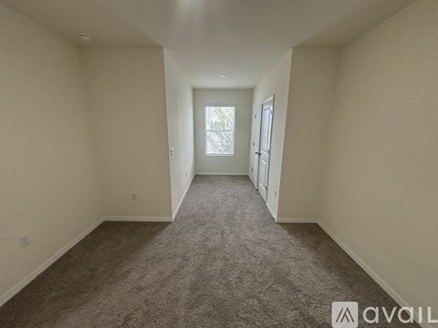 A spacious room with carpeted floor and a window letting in natural light.