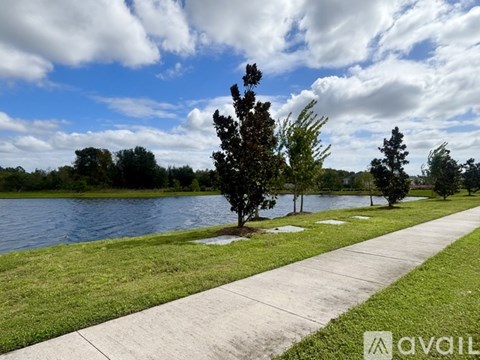 A walkway runs alongside a body of water with trees on the side.