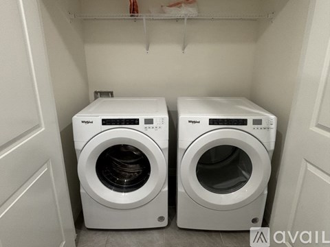 Two white Whirlpool washing machines in a small laundry room.
