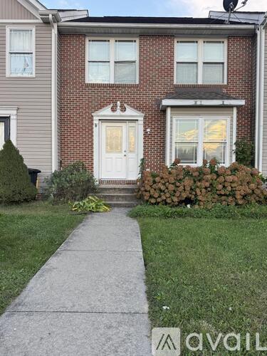 A brick house with a white door and a small front yard.