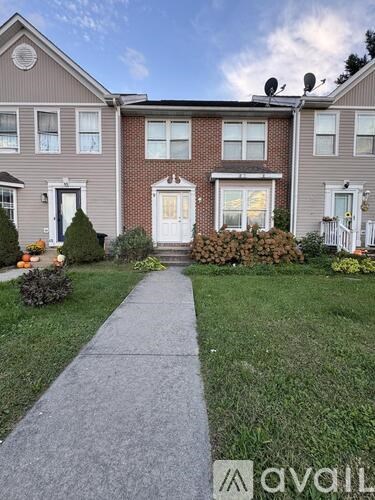 A house with a front yard and a sidewalk leading to the front door.