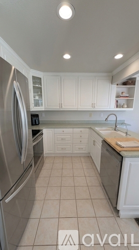 A kitchen with white cabinets and a stainless steel refrigerator.