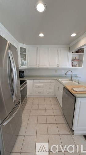 A kitchen with white cabinets and a stainless steel refrigerator.