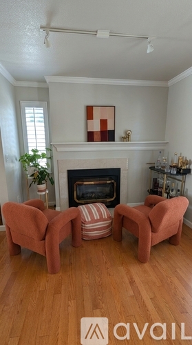 A living room with a fireplace and two chairs.