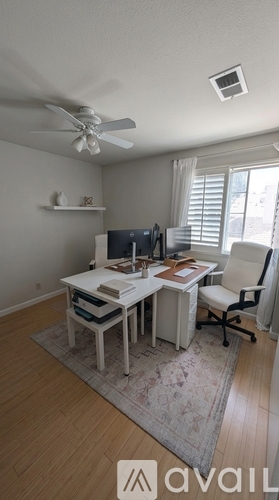 A room with a desk and a fan.