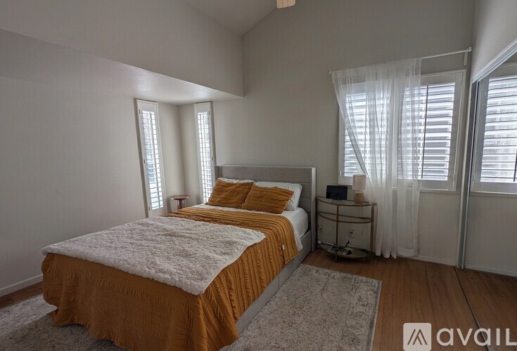 A bedroom with a bed, nightstand, and window with curtains.