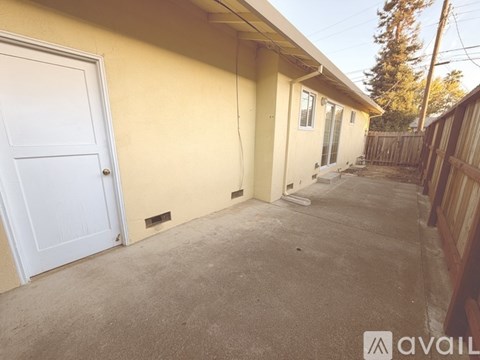 A white door is on the left of a yellow house.