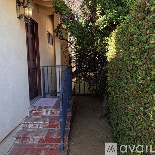 A small alley with a metal railing and steps leading to a door.