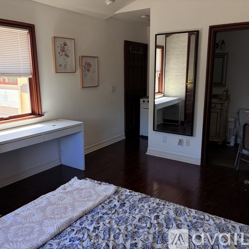A bedroom with a bed, a window seat, and a mirror.