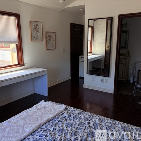 A bedroom with a bed, a window seat, and a mirror.