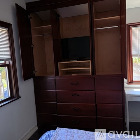 A bedroom with a bed, desk, and a large wardrobe with a mirror.