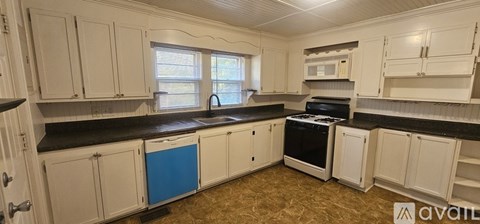 A kitchen with white cabinets and black countertops is available.