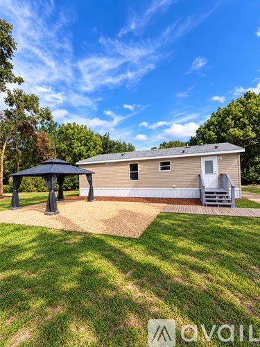 A house with a covered patio and a well-kept lawn.