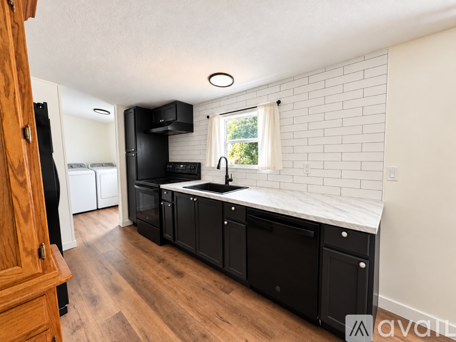 A kitchen with black appliances and wooden floors.
