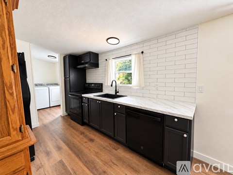 A kitchen with black appliances and wooden floors.