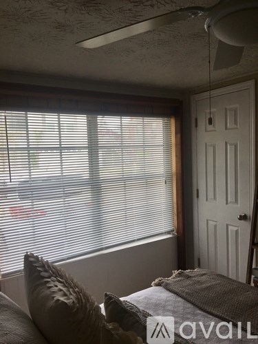 A room with a bed and a window with blinds.