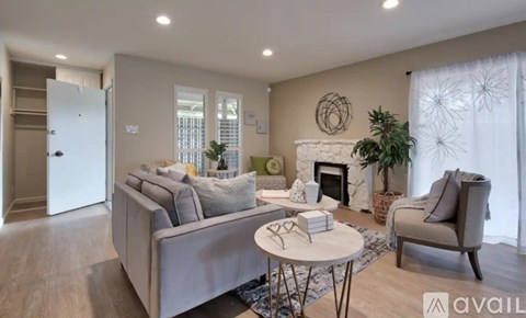 A living room with a grey couch, a white coffee table, and a fireplace.