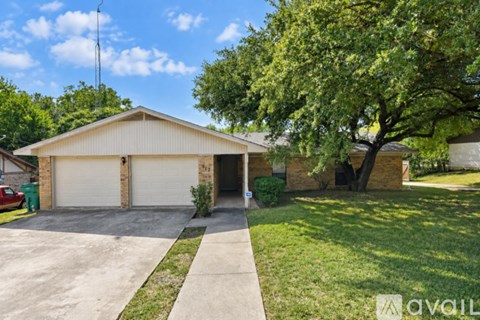 A house with a garage and a tree in front.