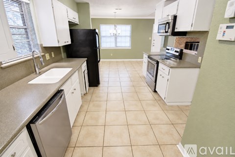 A kitchen with white cabinets and a black refrigerator.