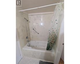A white bathroom with a shower curtain and a shower head.