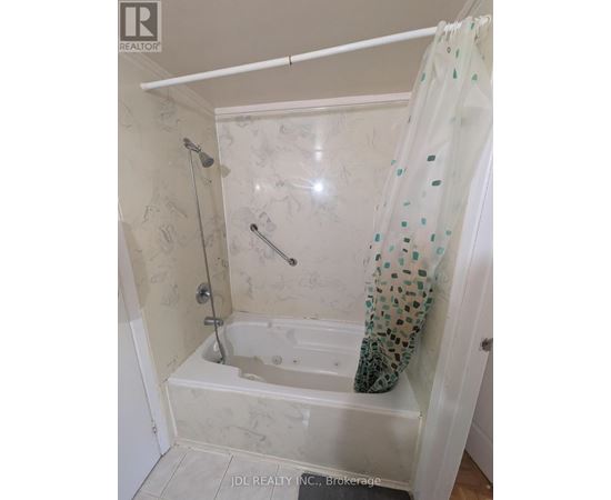 A white bathroom with a shower curtain and a shower head.