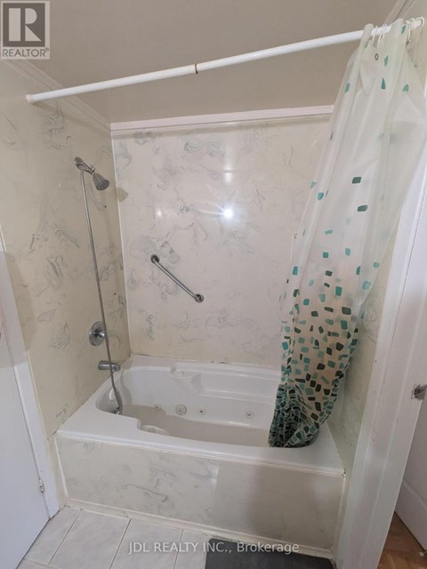 A white bathroom with a shower curtain and a shower head.