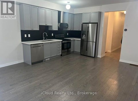 A kitchen with a refrigerator, sink, and cabinets.