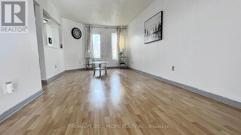 A spacious room with wooden flooring and a dining table set up with chairs.