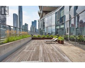 A wooden deck with a bench and potted plants on a balcony overlooking a city skyline.