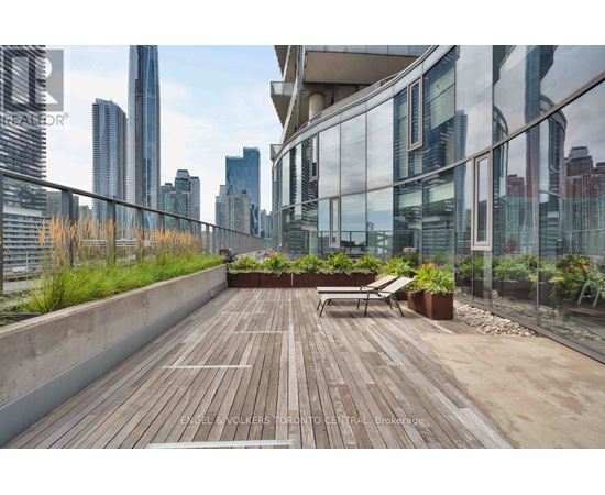 A wooden deck with a bench and potted plants on a balcony overlooking a city skyline.