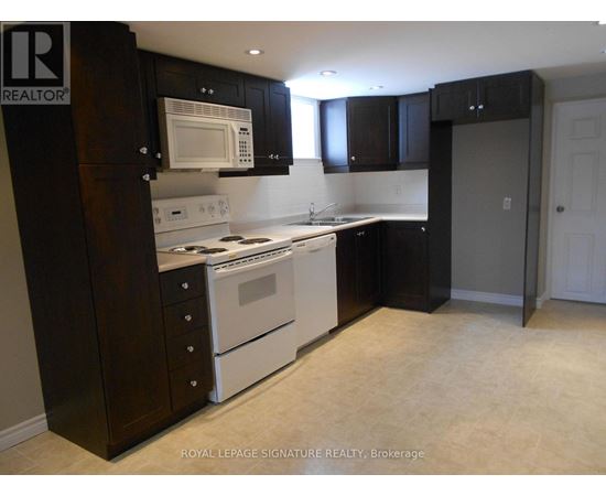 A kitchen with a white stove top oven and microwave, and black cabinets.