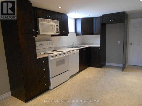 A kitchen with a white stove top oven and microwave, and black cabinets.